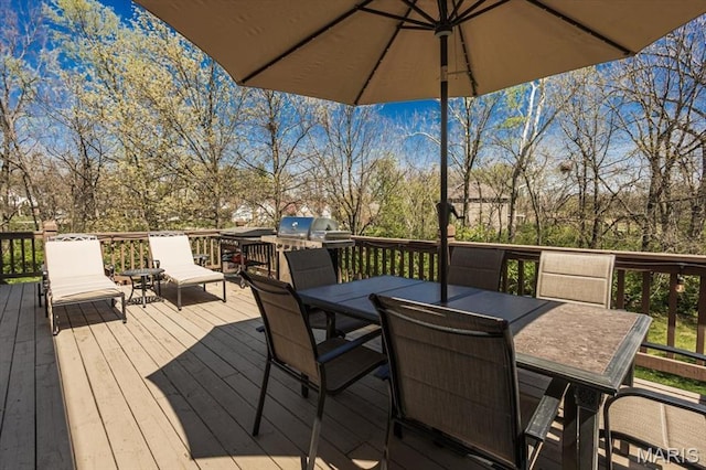 wooden terrace with outdoor dining space and view of scattered trees