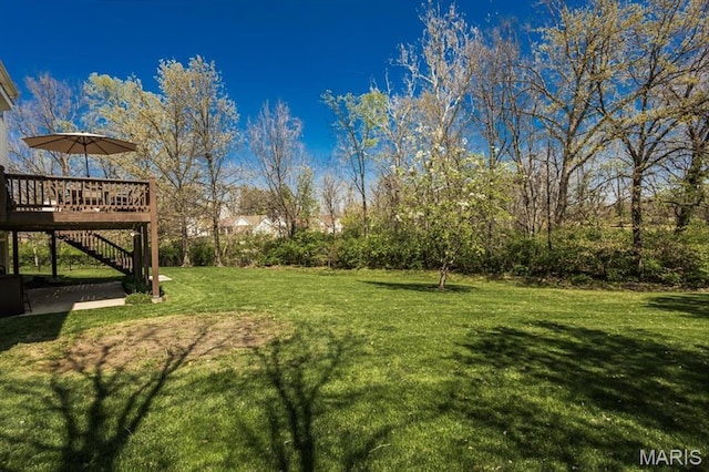 view of grassy yard featuring stairway and a deck