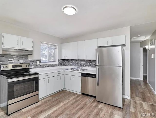1749 Foley Dr, Saint Louis, MO 63136 - kitchen with appliances with stainless steel finishes, under cabinet range hood, light countertops, decorative backsplash, and light wood-style flooring