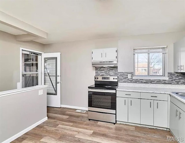 1749 Foley Dr, Saint Louis, MO 63136 - kitchen with stainless steel electric stove, under cabinet range hood, light countertops, tasteful backsplash, and baseboards
