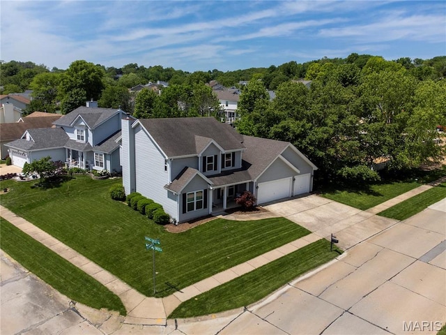 view of front of house featuring concrete driveway, a front yard, and a garage