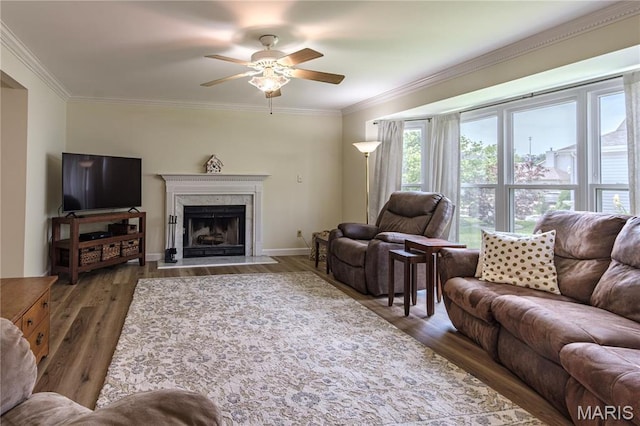 living room with ceiling fan, wood finished floors, crown molding, a premium fireplace, and baseboards