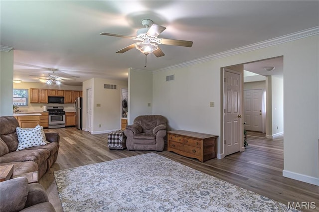 living area with ceiling fan, baseboards, wood finished floors, and crown molding