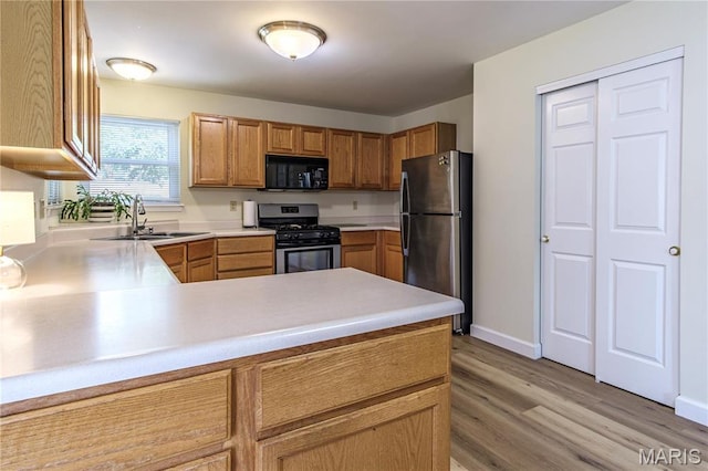 kitchen featuring stainless steel appliances, a sink, light wood-style flooring, and light countertops
