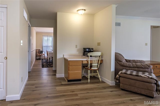 office space with wood finished floors, baseboards, and crown molding