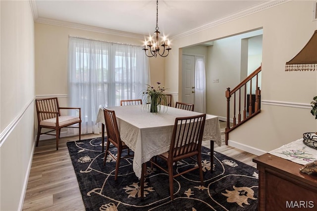 dining space with a chandelier, light wood-style flooring, ornamental molding, stairs, and baseboards