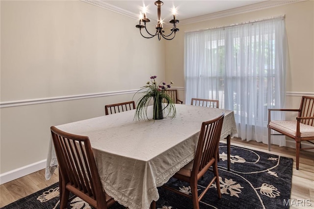 dining space with crown molding, a chandelier, light wood-style floors, and baseboards