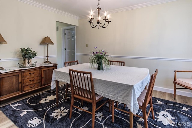 dining room with a chandelier, wood finished floors, crown molding, and baseboards
