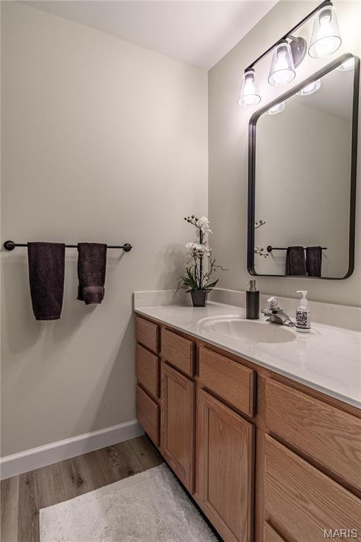 bathroom with wood finished floors, vanity, and baseboards