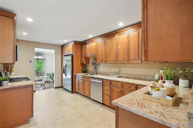 13112 Royal Pines Dr, Saint Louis, MO 63146 - kitchen featuring stainless steel appliances, brown cabinets, recessed lighting, light stone countertops, and a chandelier