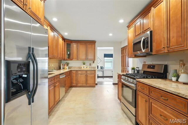 13112 Royal Pines Dr, Saint Louis, MO 63146 - kitchen with stainless steel appliances, brown cabinetry, light stone counters, recessed lighting, and glass insert cabinets