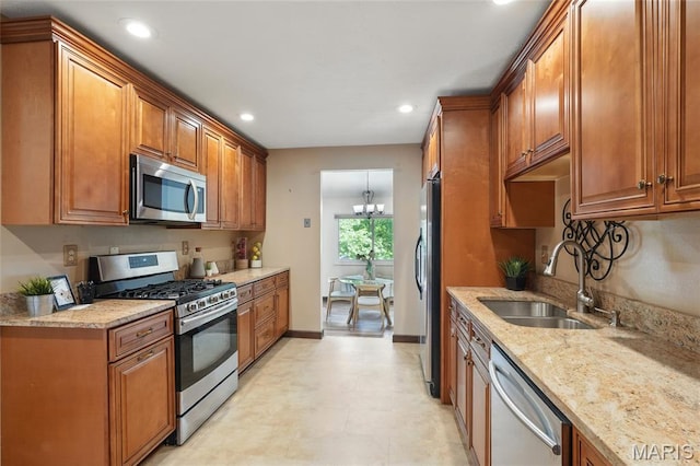 13112 Royal Pines Dr, Saint Louis, MO 63146 - kitchen featuring appliances with stainless steel finishes, a sink, brown cabinetry, light stone counters, and recessed lighting
