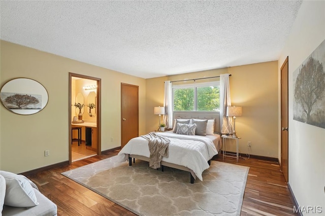 13112 Royal Pines Dr, Saint Louis, MO 63146 - bedroom featuring wood finished floors, a textured ceiling, baseboards, and connected bathroom