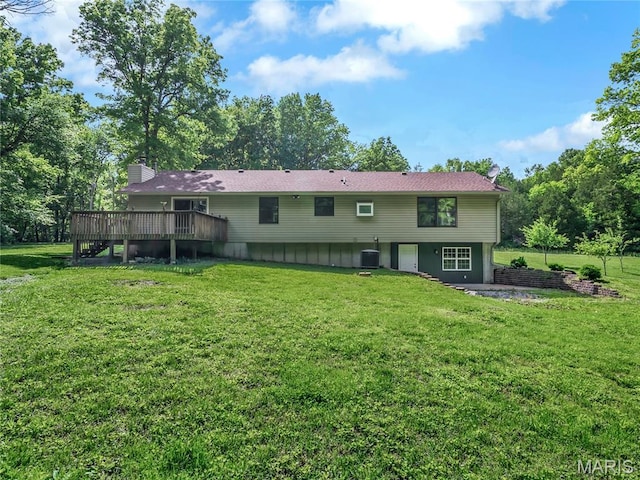 back of property featuring a deck, a yard, a chimney, and central AC unit