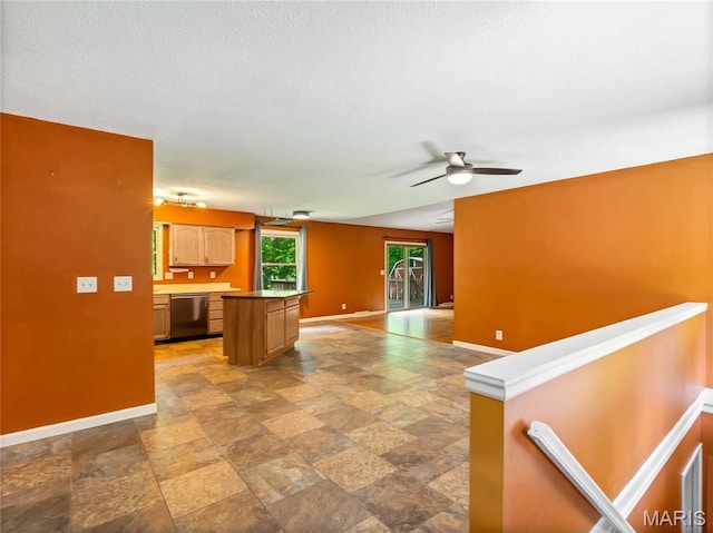 kitchen with dishwasher, baseboards, light stone finish floors, a kitchen island, and open floor plan