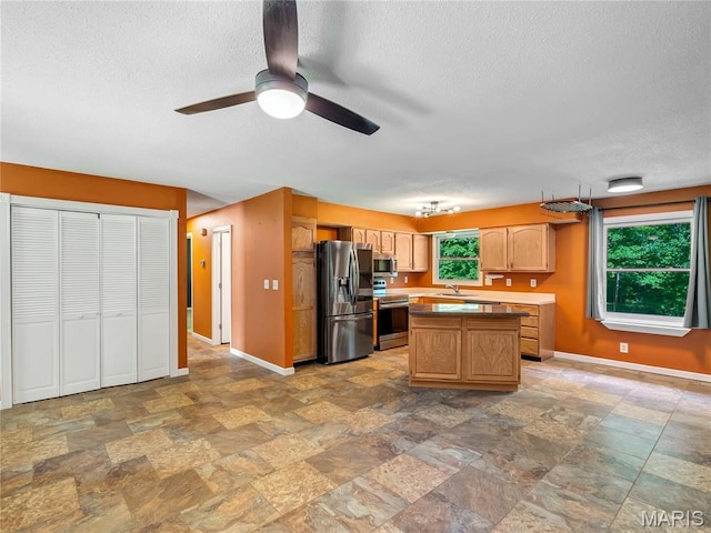 kitchen with stainless steel appliances, a sink, a textured ceiling, baseboards, and stone finish floors