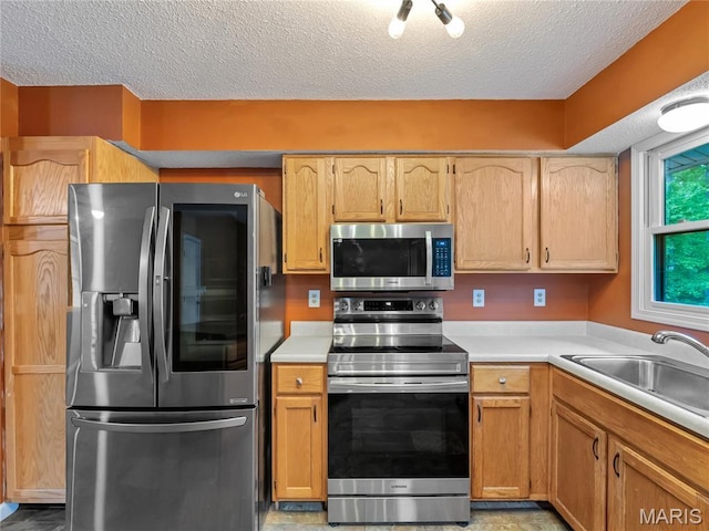 kitchen with stainless steel appliances, a textured ceiling, light countertops, and a sink