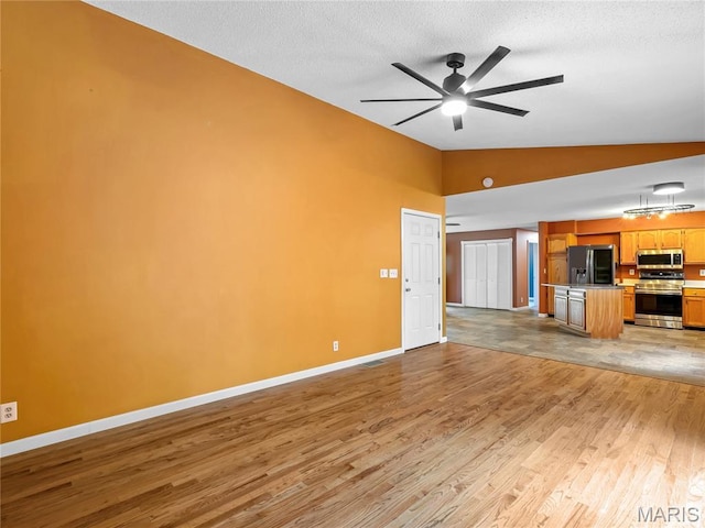 unfurnished living room featuring vaulted ceiling, light wood-style flooring, baseboards, ceiling fan, and a textured ceiling