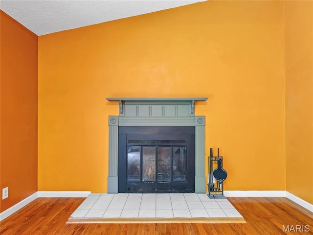 detailed view of a fireplace with flush hearth, wood finished floors, and baseboards