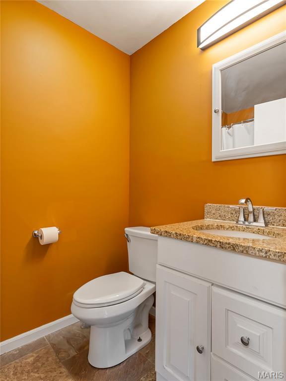 bathroom featuring baseboards, toilet, and vanity