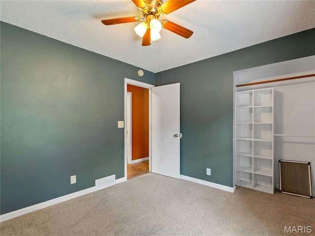 unfurnished bedroom featuring carpet, baseboards, ceiling fan, and a textured ceiling