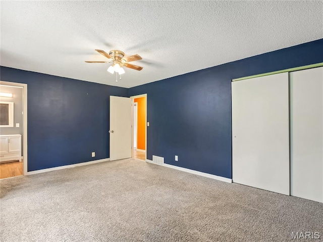 unfurnished bedroom with carpet flooring, a closet, baseboards, a textured ceiling, and ceiling fan