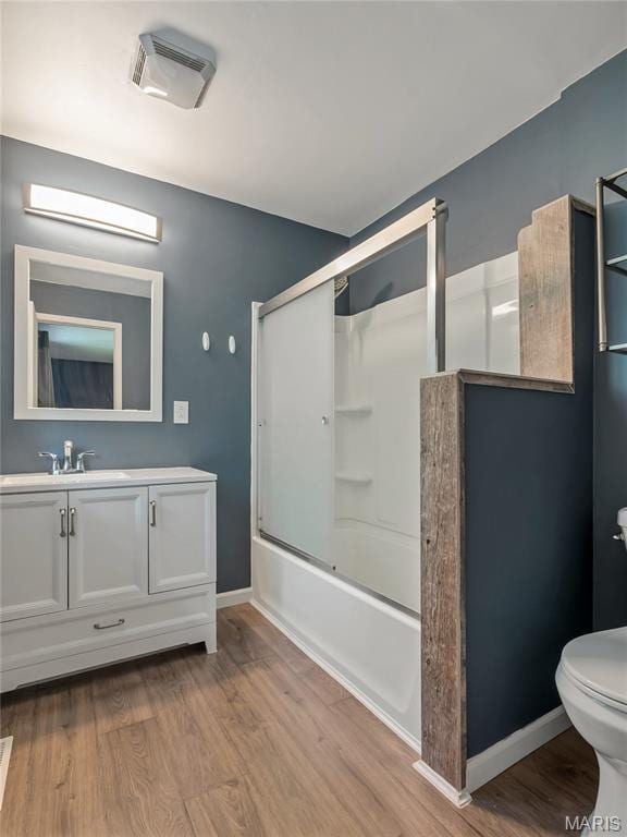full bath with wood finished floors, toilet, vanity, enclosed tub / shower combo, and baseboards