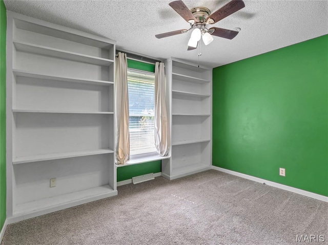 unfurnished room with a textured ceiling, carpet flooring, baseboards, and ceiling fan