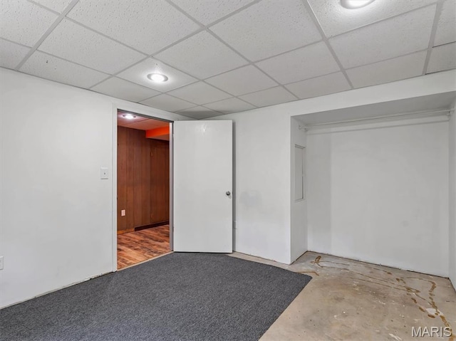 finished basement featuring a drop ceiling and wood walls