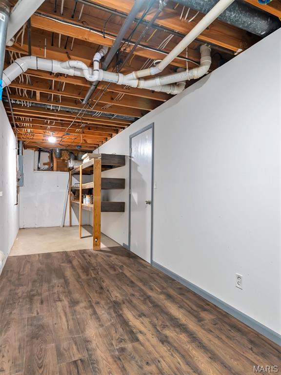unfinished basement with wood finished floors and electric panel