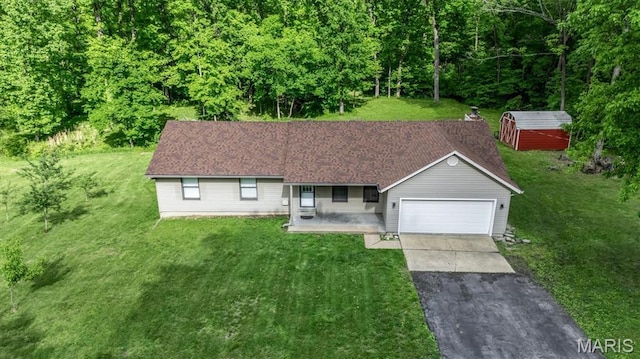 single story home with asphalt driveway, an attached garage, a front lawn, covered porch, and a storage shed