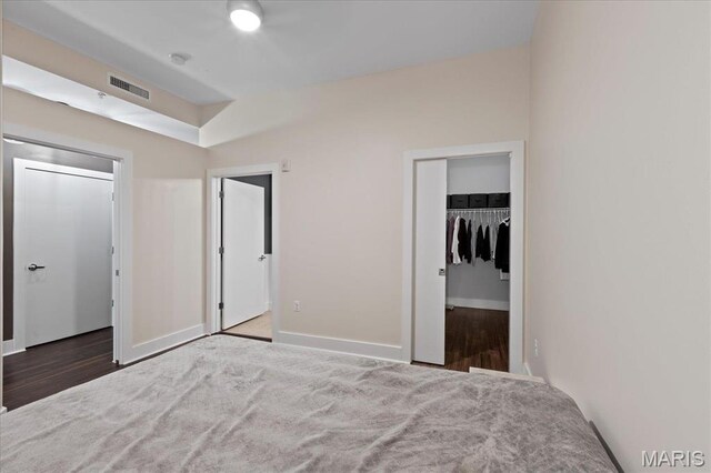 9 N Euclid Ave Unit 411, Saint Louis, MO 63108 - unfurnished bedroom with a walk in closet, baseboards, wood finished floors, and a closet