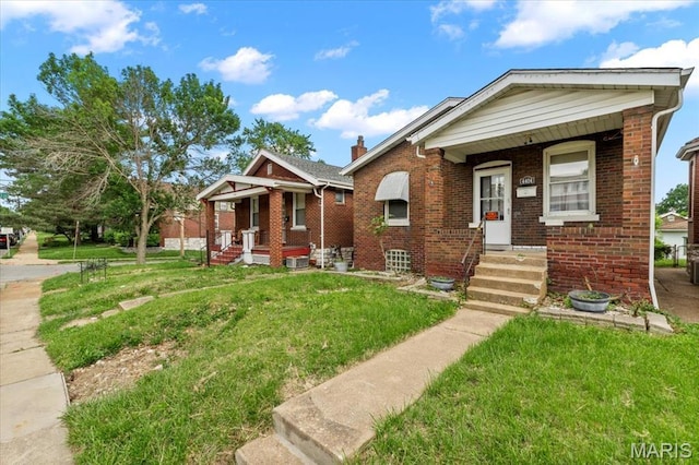 bungalow-style house with covered porch, a front lawn, brick siding, and a chimney