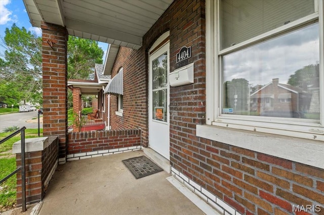 view of exterior entry featuring a porch and brick siding