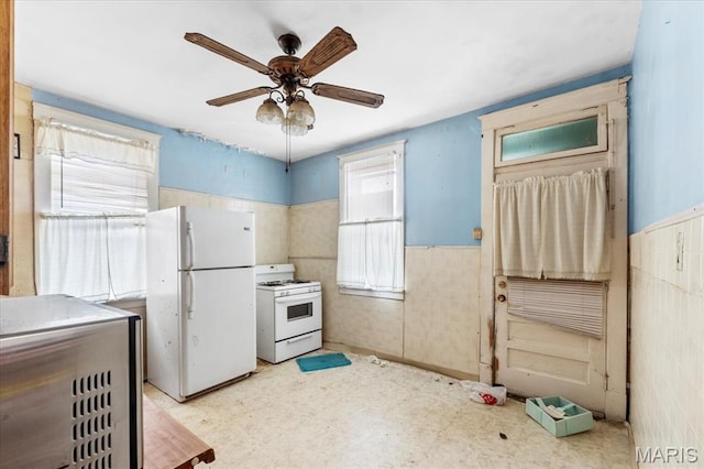 kitchen featuring white appliances, a wainscoted wall, a ceiling fan, and tile patterned floors