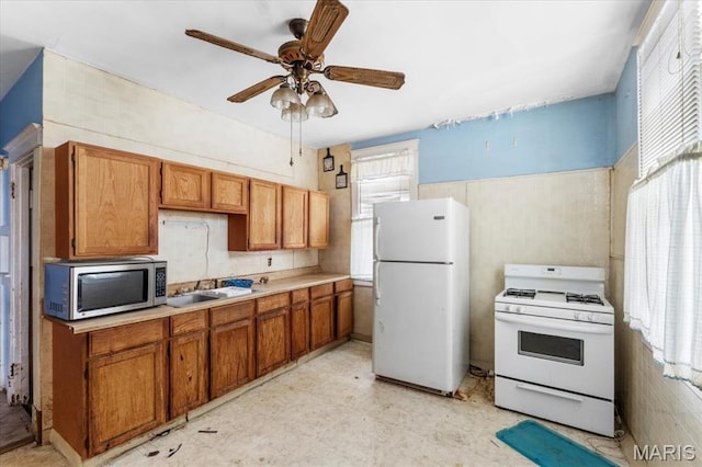 kitchen featuring white appliances, healthy amount of natural light, light floors, and a ceiling fan