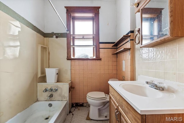bathroom featuring tile walls, toilet, vanity, tile patterned flooring, and a wainscoted wall