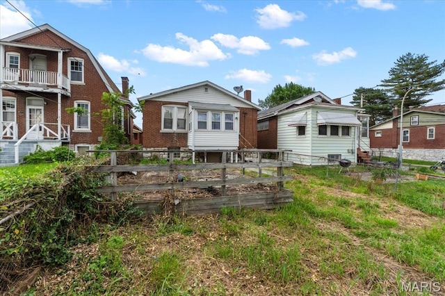 back of property featuring fence, a garden, and brick siding