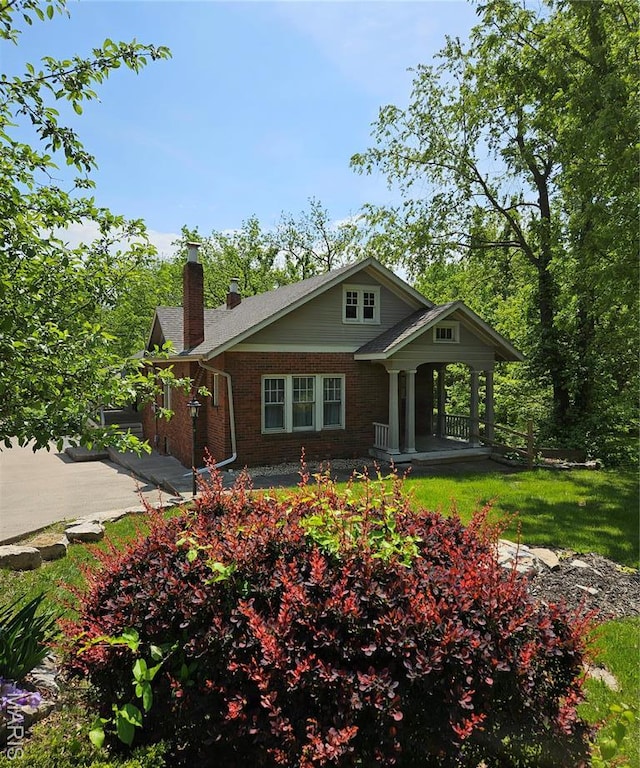 view of front of property with a chimney, brick siding, and a porch