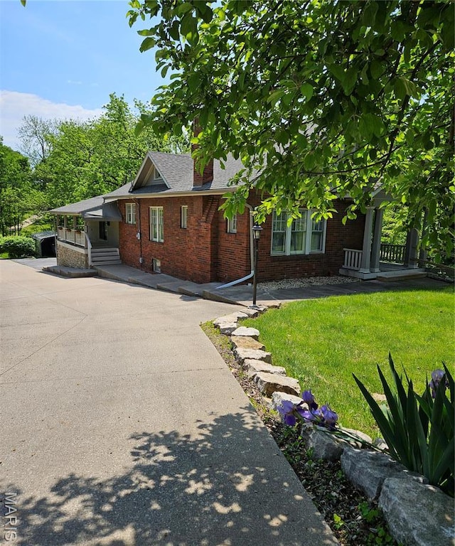 view of home's exterior featuring brick siding, a yard, and a chimney