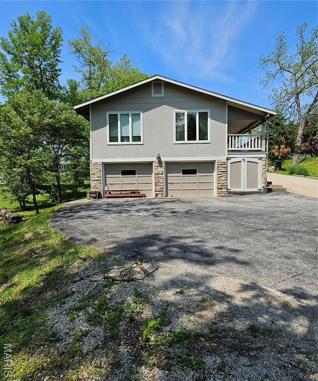 view of side of home with stone siding, a garage, and driveway