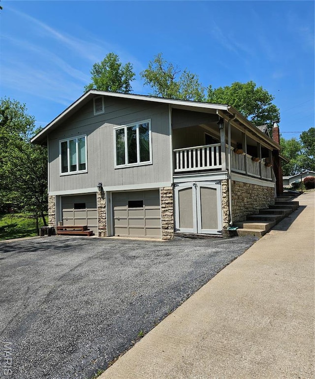 view of front of house featuring stone siding, an attached garage, and asphalt driveway