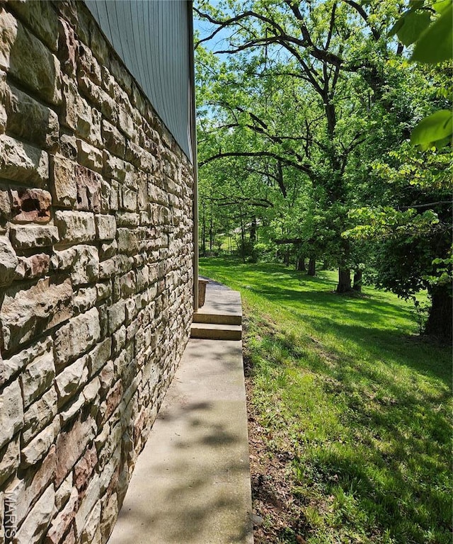 view of property exterior featuring stone siding and a lawn