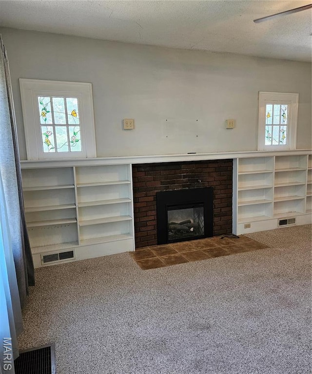 unfurnished living room with carpet flooring and a brick fireplace