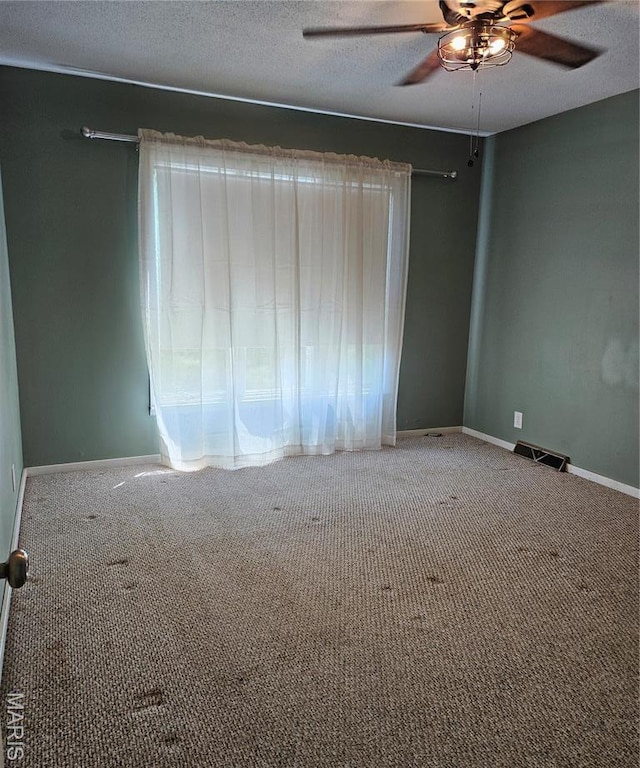 carpeted spare room featuring a ceiling fan, baseboards, and a textured ceiling
