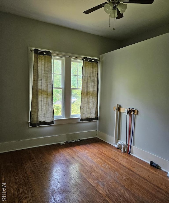 spare room with a ceiling fan, wood finished floors, and baseboards