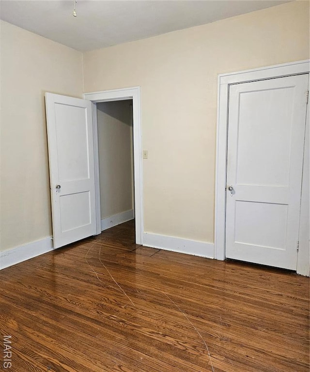 unfurnished bedroom with wood finished floors and baseboards