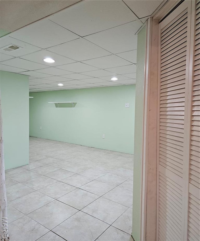 below grade area with recessed lighting, a paneled ceiling, and light tile patterned flooring