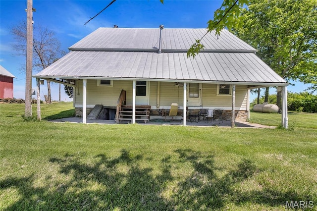 back of house with a lawn, metal roof, and a patio area
