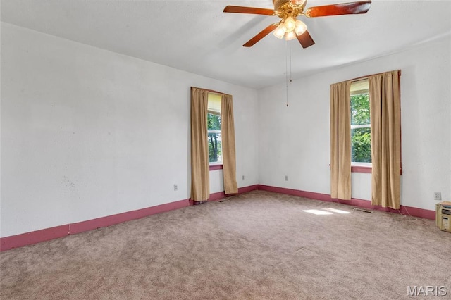 carpeted empty room with a ceiling fan and baseboards